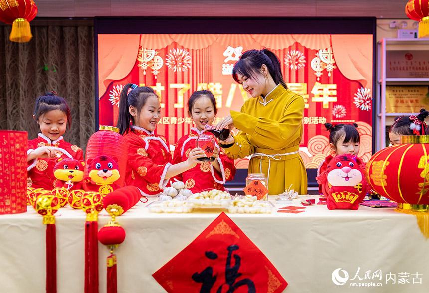 I bambini imparano a marinare l'aglio sotto la guida degli insegnanti al Palazzo della Gioventù nel distretto di Yuquan, Hohhot. (Quotidiano del Popolo Online/Ding Genhou)