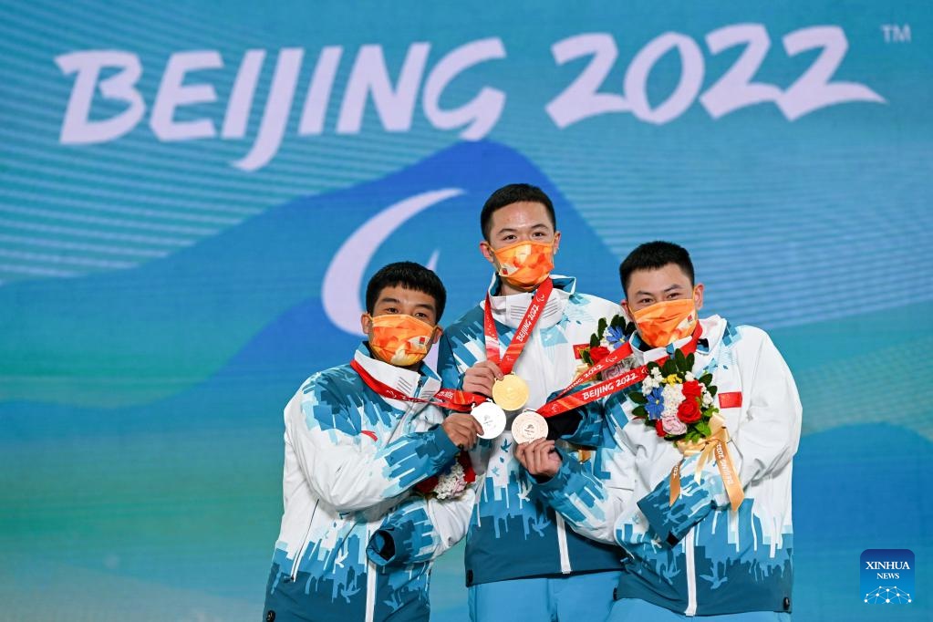 La medaglia d'oro Ji Lijia, la medaglia d'argento Wang Yaopeng (a sinistra) e la medaglia di bronzo Zhu Yonggang della Cina posano per le foto durante la cerimonia di premiazione dell'evento Para Snowboard Men's Snowboard Cross SB-UL dei Giochi Paralimpici Invernali di Beijing 2022 alla Medals Plaza di Zhangjiakou, nella provincia cinese settentrionale dell'Hebei. (7 marzo 2022 - Xinhua/Hu Chao)