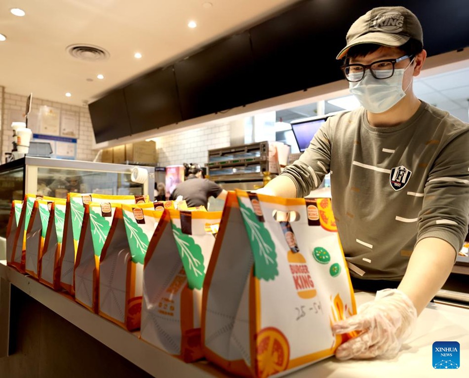 Un dipendente prepara gli ordini online per la consegna in un ristorante Burger King di Shanghai. (10 aprile 2022 - Xinhua/Chen Jianli)