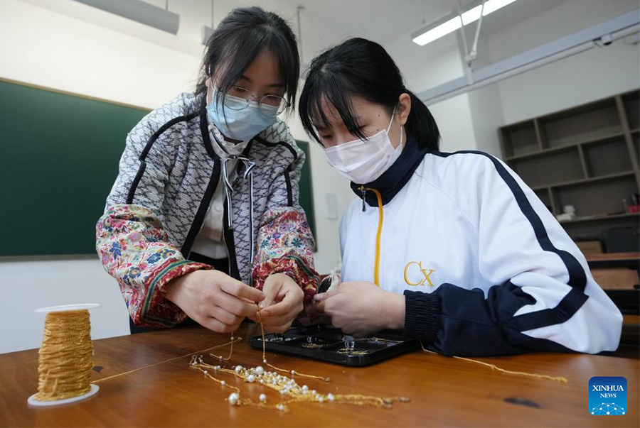 Tian Lei (L), insegnante di artigianato, insegna la lavorazione dei gioielli a una studentessa con problemi di udito nella Shaanxi Urban Economy School di Xi'an, nella provincia dello Shaanxi, Cina nord-occidentale. (13 maggio 2022 - Xinhua/Li Yibo)