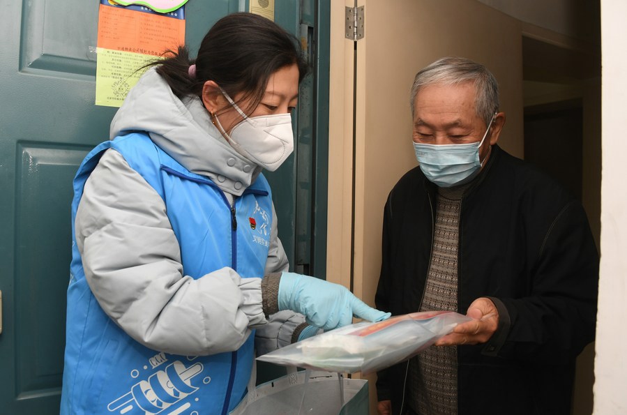 Un'addetta della comunità (a sinistra) spiega a un residente il contenuto di un pacchetto di assistenza in una comunità nel distretto Haidian di Beijing. (27 dicembre 2022 - Xinhua/Ren Chao)