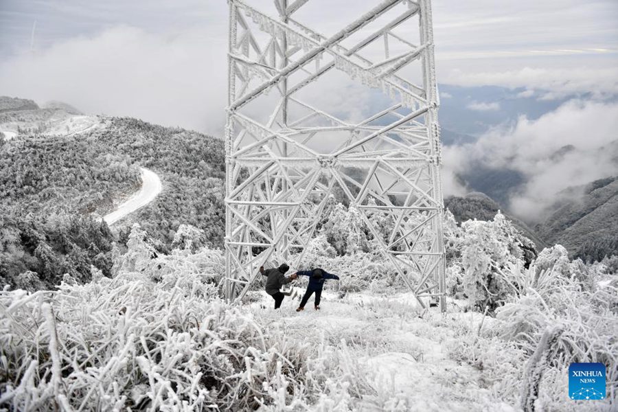I tecnici della fornitura elettrica Yin Bin (a destra) e Long Yujun controllano le condizioni di congelamento di una torre di trasmissione di energia in una stazione di osservazione sul monte Xihuang, nella provincia centrale cinese dello Hunan. (19 dicembre 2023 - Xinhua/Chen Zhenhai)