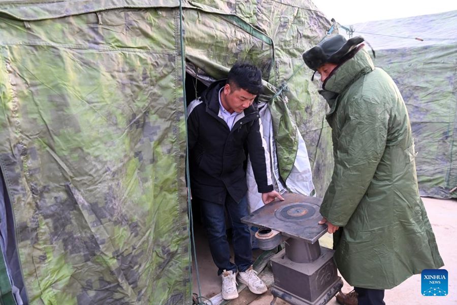 Un addetto distribuisce una stufa-fornello per un residente colpito dal terremoto nel villaggio di Zhangguojia, nella contea di Jishishan, provincia del Gansu. (20 dicembre 2023-Xinhua/Fan Peishen)