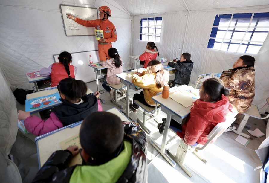 Un vigile del fuoco insegna ai bambini all'interno di una "scuola tenda" nel villaggio di Shiyuan, nella contea di Jishishan, provincia del Gansu. (21 dicembre 2023 - Wei Xiaohao/China Daily)