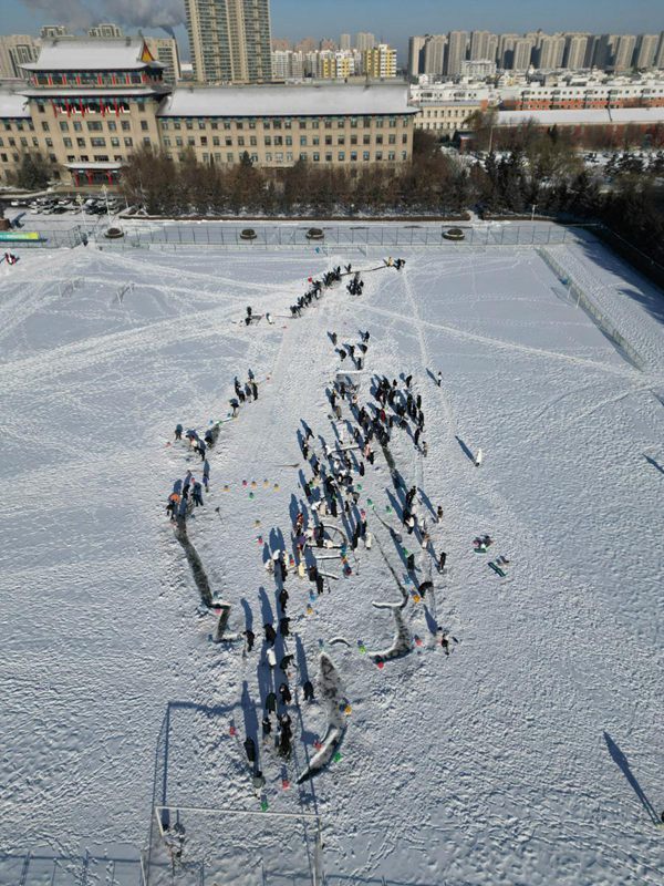 Gli studenti della Harbin Engineering University creano enormi disegni nella neve per dare il benvenuto al nuovo anno