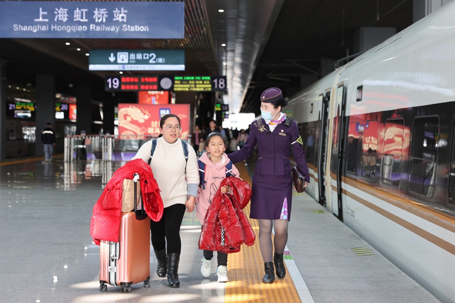 Un membro dell'equipaggio di cabina guida i passeggeri sul treno alla stazione Hongqiao di Shanghai. (17 febbraio 2024 – Xinhua)
