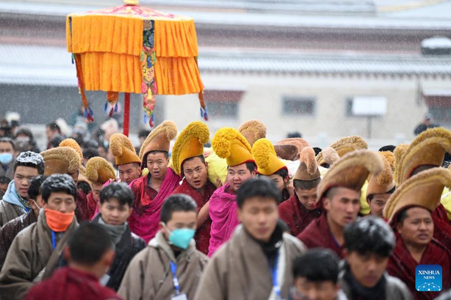 Monaci trasportano un enorme dipinto Thangka raffigurante l'immagine del Buddha durante la cerimonia annuale dell'"esposizione del Buddha al sole" del monastero di Labrang nella provincia del Gansu. (22 febbraio 2024 - Xinhua/Chen Bin)