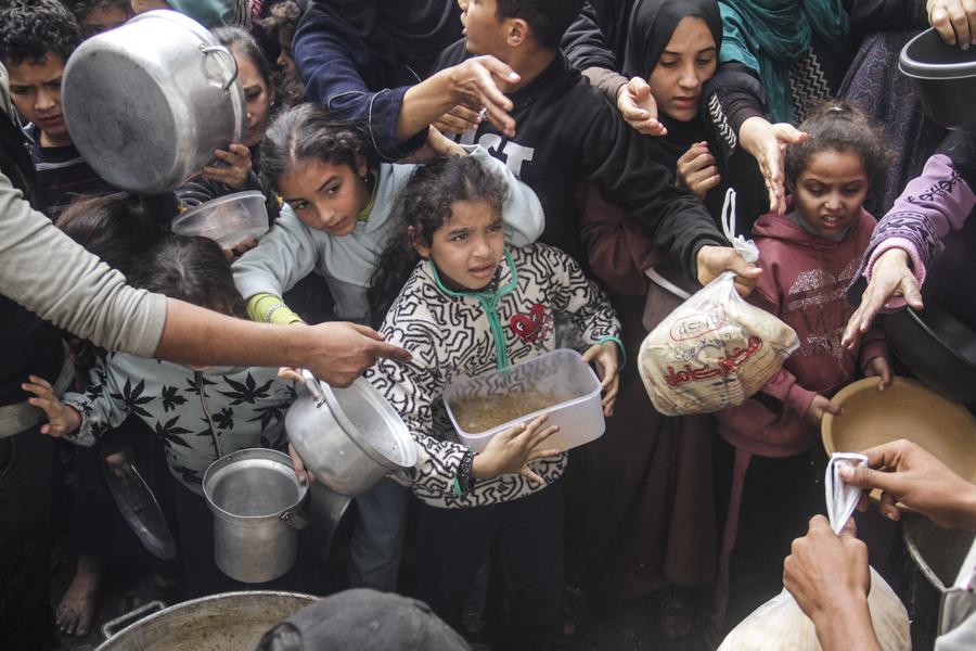 Palestinesi sfollati cercano di ottenere aiuti alimentari da una mensa della comunità locale durante l'assedio imposto dall'esercito israeliano, nel campo di Al-Shati, a ovest di Gaza. (7 dicembre 2024 - Xinhua/Mahmoud Zaki)
