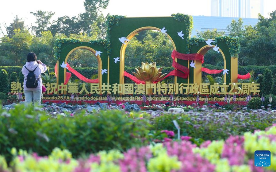 Una donna scatta foto davanti a un'installazione floreale a Macao, nel sud della Cina. (17 dicembre 2024 – Xinhua/Yao Qilin)