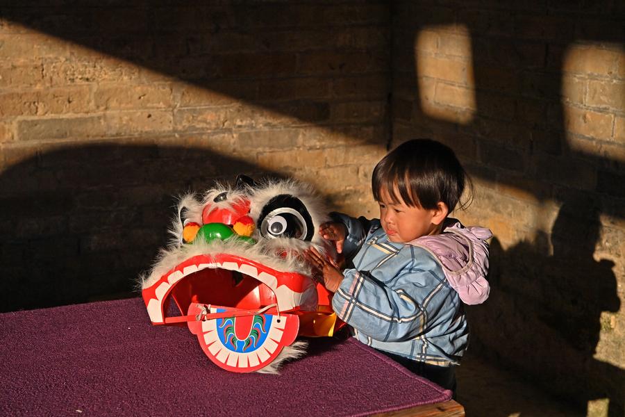 Un bambino accarezza il copricapo per la danza del leone nel villaggio di Longteng, nella regione autonoma del Guangxi Zhuang, nella Cina meridionale. (19 dicembre 2024 - Xinhua/Zhou Hua)