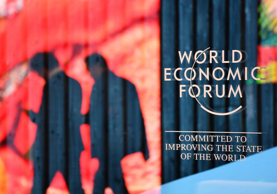 Persone camminano davanti al logo del World Economic Forum (WEF) a Davos, in Svizzera. (14 gennaio 2024 - Xinhua/Lian Yi)