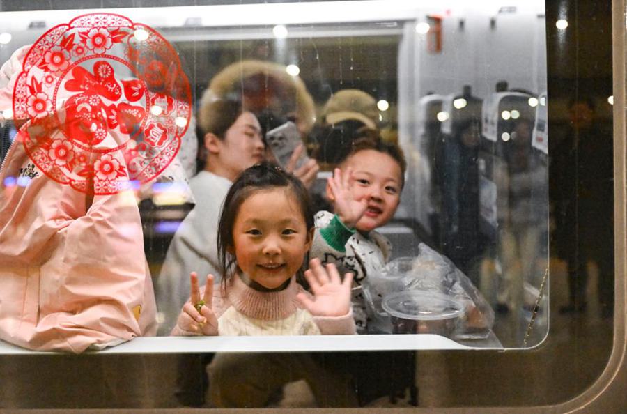 Due ragazzi fanno gesti a bordo di un treno diretto dalla stazione ferroviaria di Shanghai Hongqiao, a Shanghai, est della Cina a Guiyang, nella provincia del Guizhou, nel sud-ovest della Cina (14 gennaio 2025 - Xinhua/Chen Haoming )