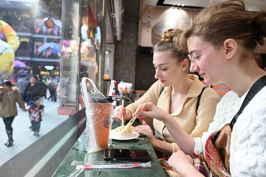 Turisti francesi gustano un jiaozi (raviolo al vapore) al centro commerciale Yuyuan Garden di Shanghai, nella Cina orientale. (21 gennaio 2025 - Xinhua/Chen Aiping)