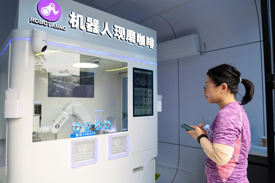 Cliente attende un caffè preparato da un robot in un parco di Shenzhen, nella provincia meridionale cinese del Guangdong. (27 dicembre 2024 - Xinhua/Liang Xu)