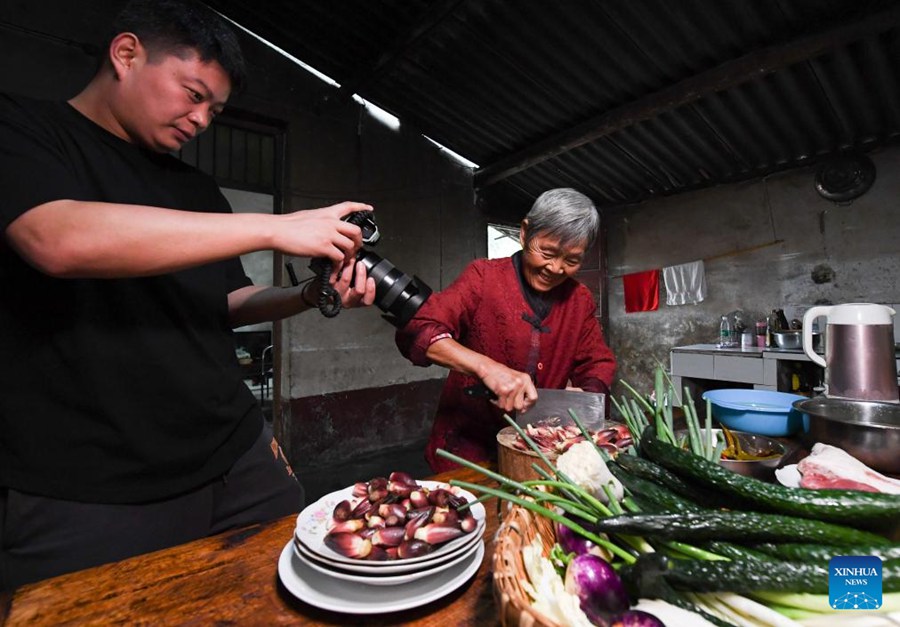 Zhang Wanlu filma la nonna mentre cucina a casa ad Ankang, nella provincia nord-occidentale dello Shaanxi. (21 settembre 2022 - Xinhua/Zou Jingyi)