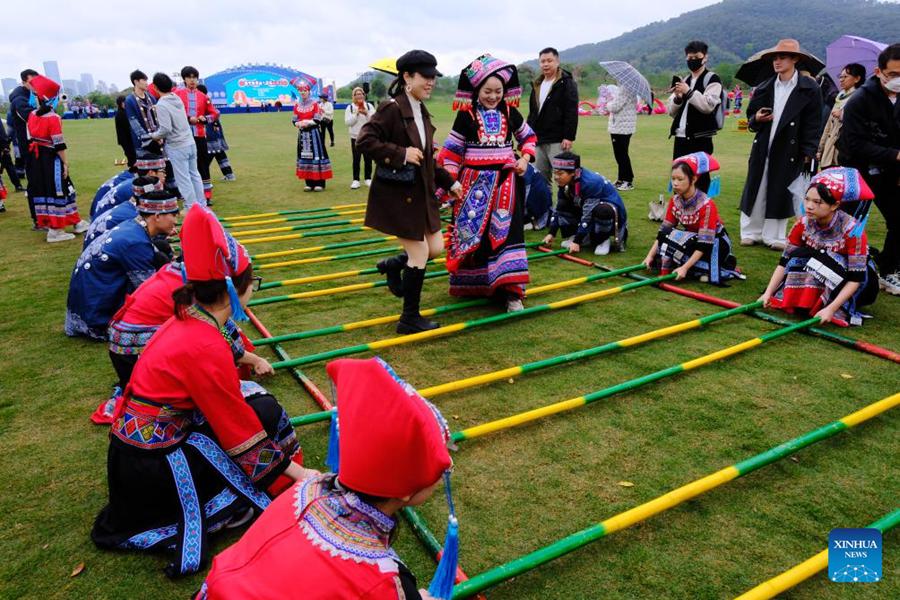 Una turista sperimenta la danza con pali di bambù nell'area panoramica del Monte Qingxiu a Nanning, nella regione autonoma del Guangxi Zhuang, nel sud della Cina. (29 marzo 2025 – Xinhua/Zhou Hua)