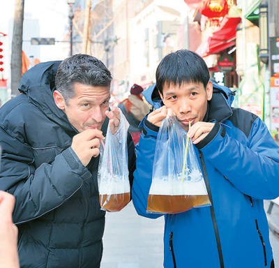 Turista straniero beve birra in sacchetto a Qingdao, nella provincia orientale cinese dello Shandong. (Foto/Xu Congjun)