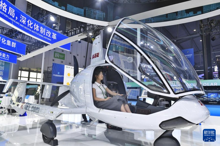 Una visitatrice prova un elicottero in esposizione durante la seconda edizione della Conferenza per gli scambi scientifici e tecnologici della Belt and Road a Chengdu, nella provincia del Sichuan. (11 giugno 2025 – Xinhua/Liu Kun)