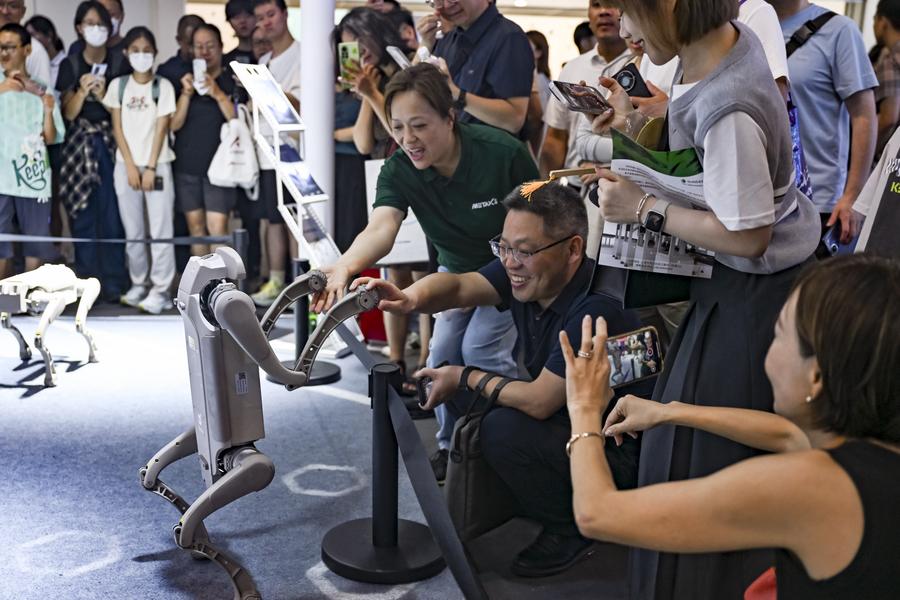 Visitatori interagiscono con un cane robot alla Conferenza Mondiale sull'Intelligenza Artificiale (WAIC) del 2025 a Shanghai, nella Cina orientale. (29 luglio 2025 - Xinhua/Chen Haoming)