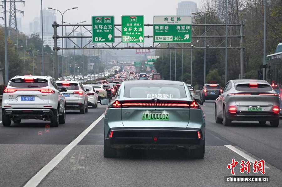 Un veicolo a guida autonoma di livello L3 con targa "YU AD0001Z" percorre una strada rapida urbana di Chongqing. (24 dicembre 2025 – Chinanews/He Penglei)