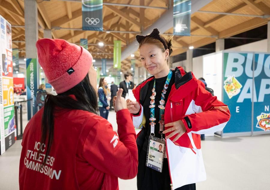 L'atleta cinese Yang Binyu (a destra) scambia una spilla con un membro dello staff del Villaggio Olimpico a Milano. (3 febbraio 2026 - Xinhua/Zhang Haofu)