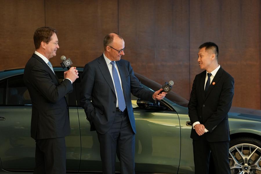 Il cancelliere tedesco Friedrich Merz (al centro) comunica con Ola Kaellenius (a sinistra), CEO del gruppo Mercedes-Benz, e Cao Xudong, CEO dell'azienda tecnologica cinese Momenta, dopo aver sperimentato un sistema di assistenza alla guida pilota in ambito urbano e autostradale, sviluppato congiuntamente da Mercedes-Benz e Momenta, a Beijing, capitale della Cina. (26 febbraio 2026 - Xinhua/Ju Huanzong)