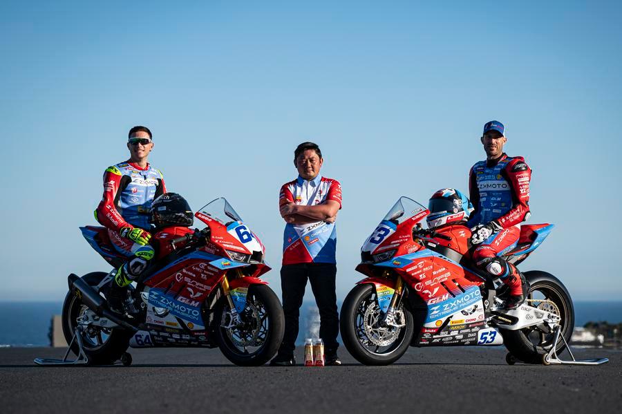 Il pilota francese Valentin Debise (a destra) e il pilota italiano Federico Caricasulo (a sinistra) posano con Zhang Xue (al centro), fondatore del marchio e proprietario del produttore cinese di motociclette ZXMOTO, presso il Phillip Island Grand Prix Circuit in Australia. (20 febbraio 2026 - Xinhua)