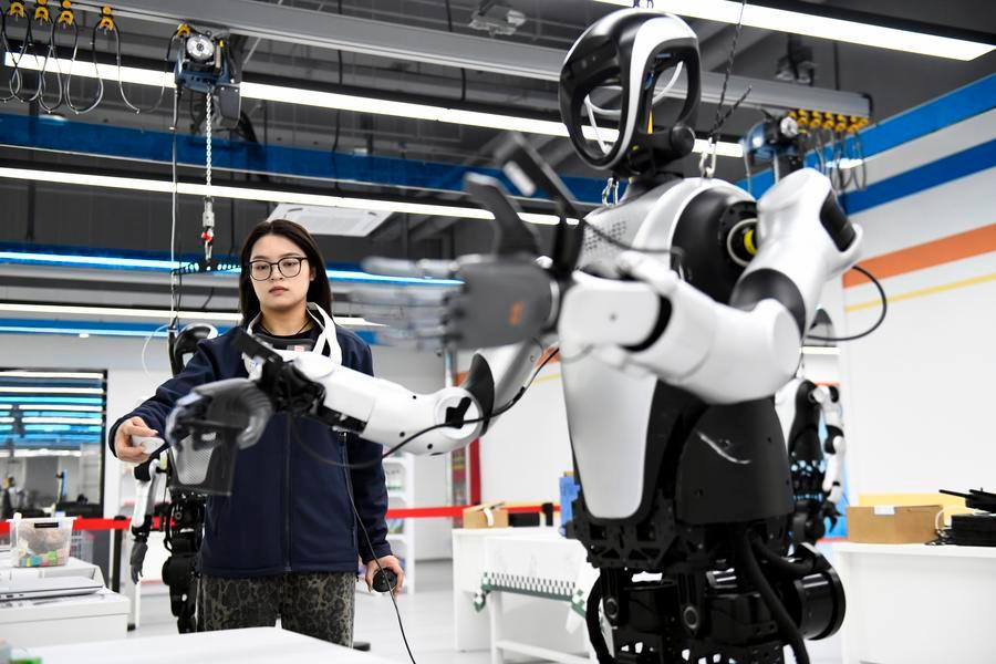 Addestratore supervisiona l'addestramento di un robot umanoide in uno scenario di pulizia domestica presso un centro di addestramento dati per l'IA incarnata nella contea di Pingyin, nella provincia dello Shandong, Cina orientale. (21 aprile 2026 - Xinhua/Guo Xulei)