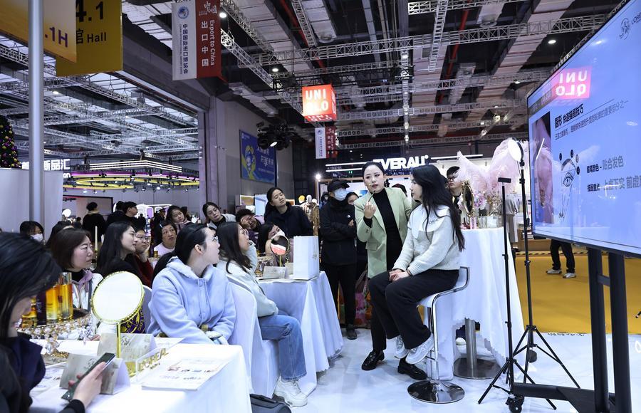 I visitatori apprendono tecniche di trucco presso lo stand L'Oréal alla CIIE U-Fair, presso il National Exhibition and Convention Center di Shanghai, nella Cina orientale. (19 dicembre 2025 - Xinhua/Fang Zhe)