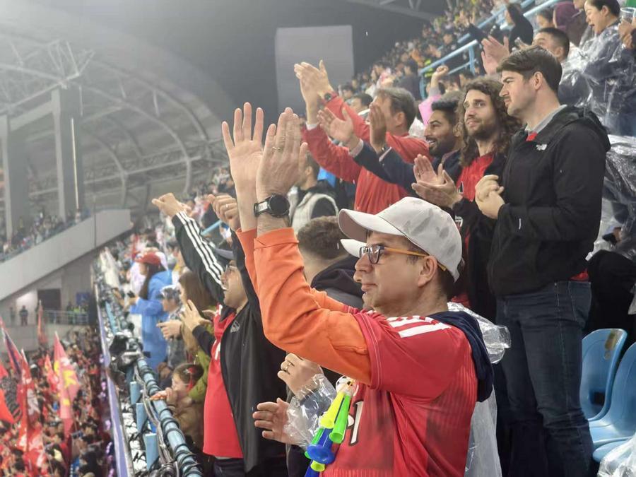 Terry Rigo (in basso) fa il tifo per il Changzhou dagli spalti durante una partita della Su Super League. (Foto fornita dall'intervistato)