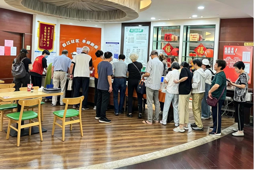 Anziani residenti della comunità di Chunjiang in fila al centro di ristorazione comunitario. (12 giugno 2026 – Quotidiano del Popolo Online/Wu Chaolan)