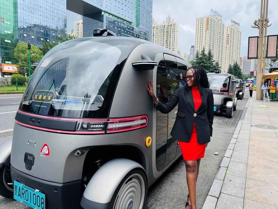 Membro di una delegazione composta da rappresentanti di partiti politici e media provenienti da 21 Paesi posa con il Potato Bus, a Guiyang, nella provincia del Guizhou, Cina sud-occidentale. (3 luglio 2026 - Xinhua/Zhou Xuanni)