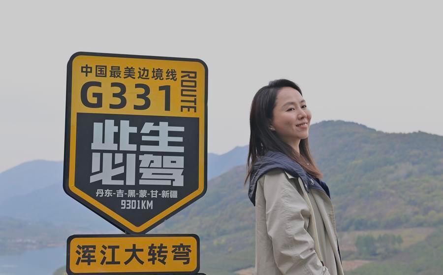 Una turista posa per una foto davanti a un cartello stradale dell’autostrada nazionale G331 nella Cina nord-orientale. (12 ottobre 2025 - Xinhua/Wu Qinghao)