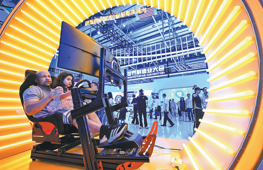Visitatore accompagna il proprio figlio a provare una cabina di guida simulata in occasione dell'apertura della World Manufacturing Convention 2026 presso l'Hefei Binhu International Convention and Exhibition Center a Hefei, nella provincia dell'Anhui. (20 settembre 2026 - Fang Dongxu/China Daily)
