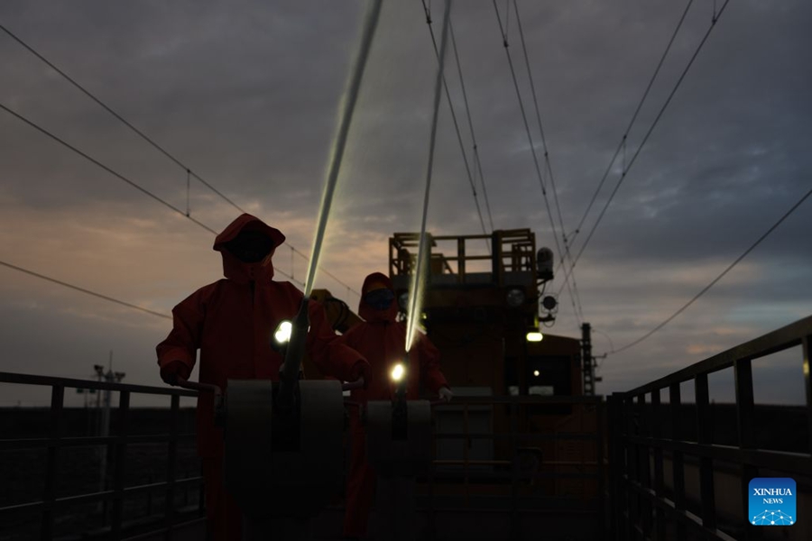 Operai puliscono gli isolatori della linea di contatto lungo la ferrovia Qinghai-Xizang